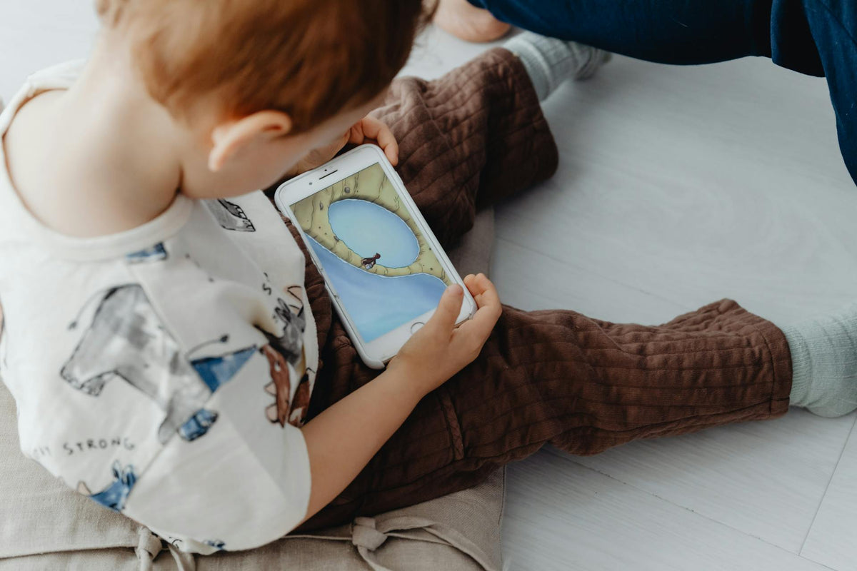 young child sitting on the floor watching videos on a smartphone instead of playing with physical toys